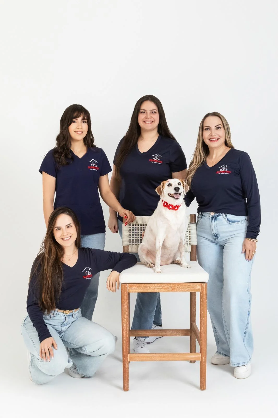 The Super Pet grooming team in navy uniforms posing with a happy dog at the salon in East Falmouth, MA